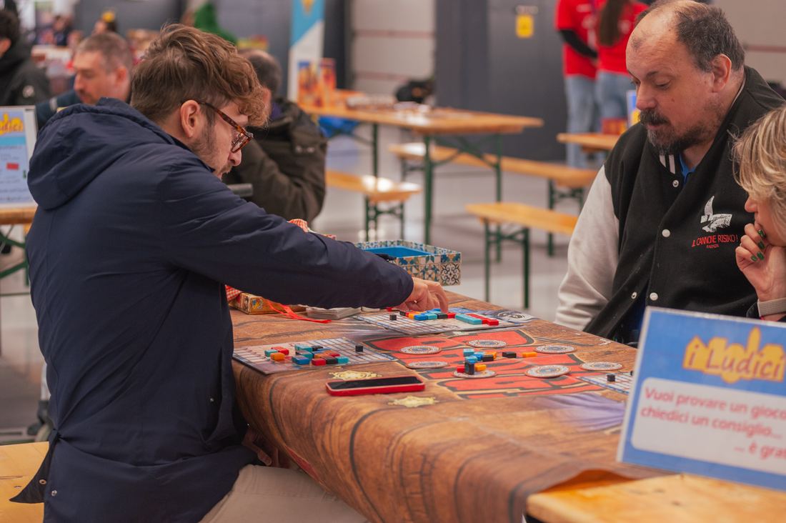 Visitatori provano giochi da tavolo ai tavoli dimostrativi